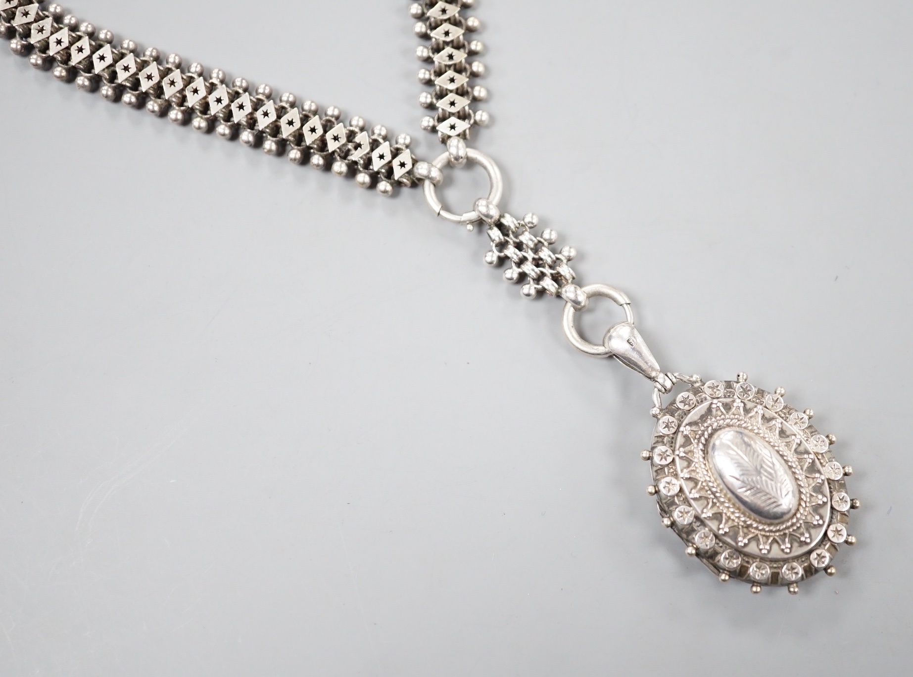 A late Victorian silver oval locket, on a white metal albertina, 49cm.